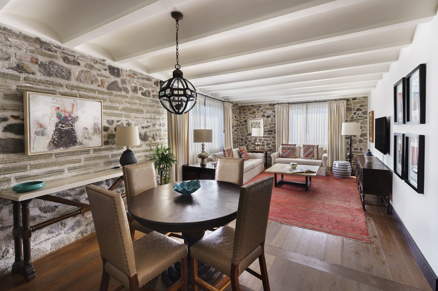 Dining table set in cozy Banyan Tree Puebla Bliss suite's living room with stone walls and elegant decor.